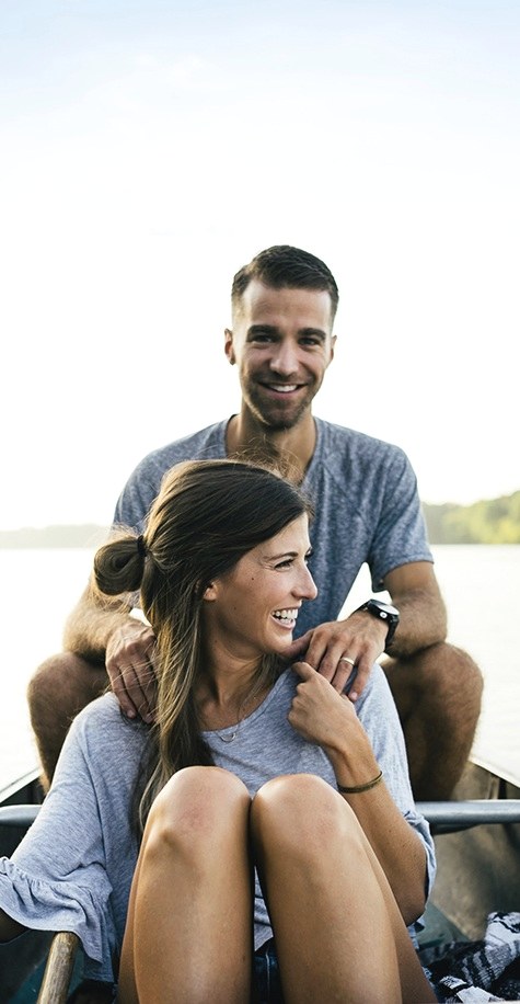 Two people sitting close together outdoors, looking out at the water