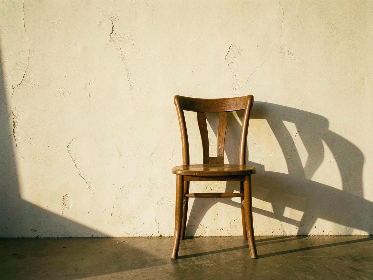 A wooden chair with books and a ceramic mug in warm light